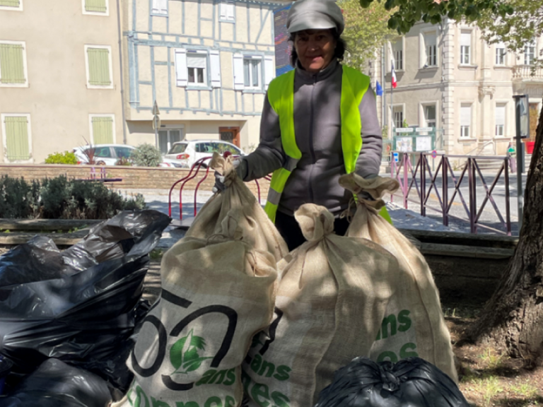 Une bénévole avec les sacs de collecte de déchets plastiques remplis suite à la marche 50 ans 50 tonnes.